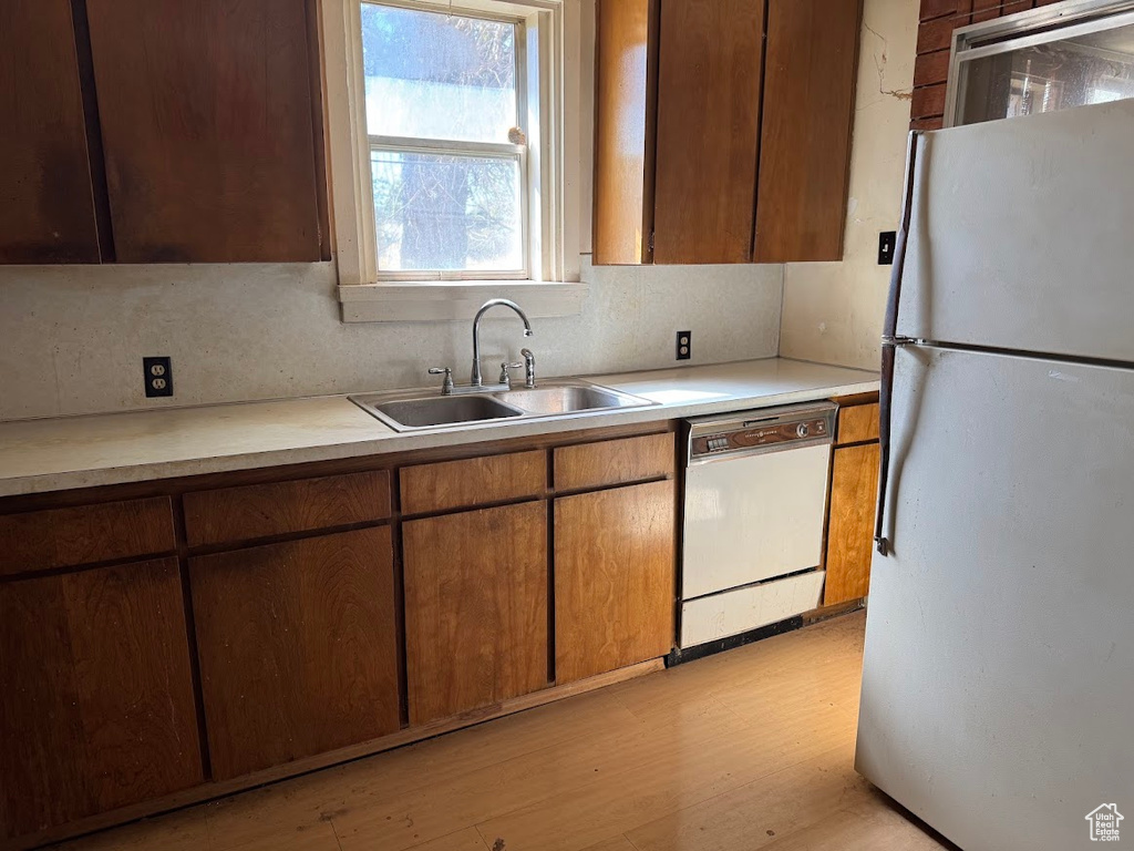 Kitchen featuring light wood-type flooring, backsplash, white appliances, and sink