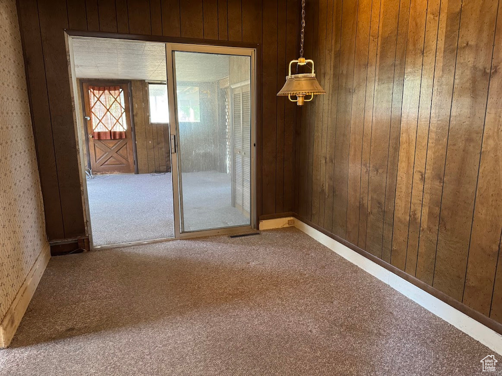 Carpeted spare room with wooden walls