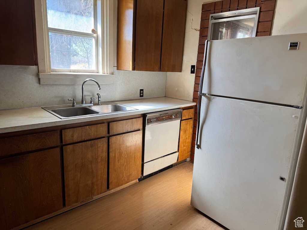 Kitchen with white appliances, light hardwood / wood-style floors, tasteful backsplash, and sink