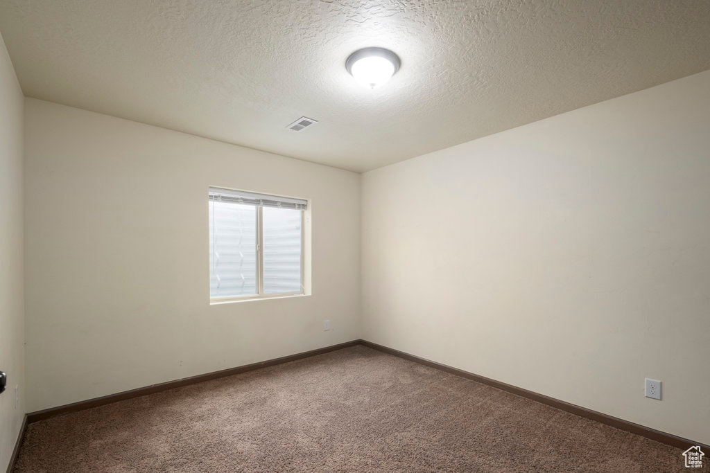 Spare room featuring a textured ceiling and carpet floors
