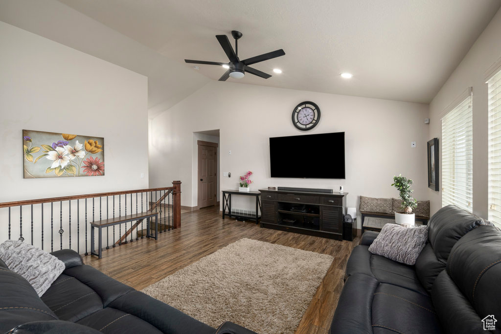 Living room featuring dark wood-type flooring, ceiling fan, and vaulted ceiling