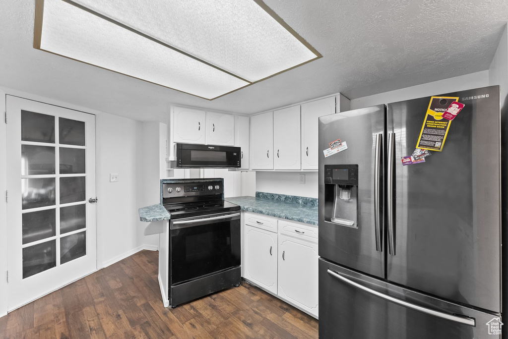 Kitchen featuring white cabinets, dark hardwood / wood-style flooring, electric range, and stainless steel refrigerator with ice dispenser