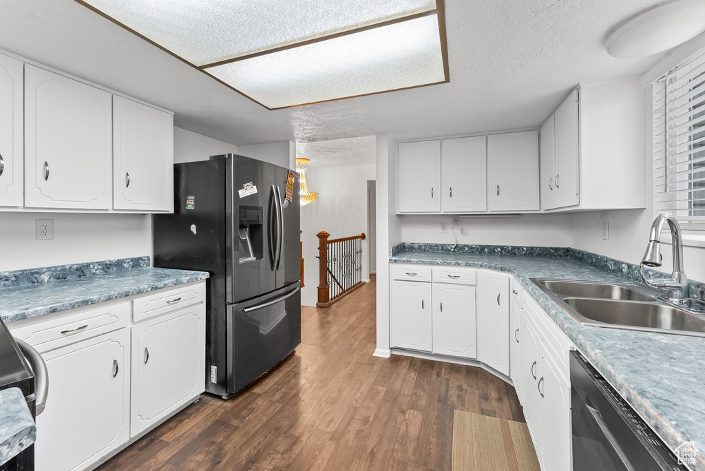 Kitchen featuring white cabinetry, dark wood-type flooring, black fridge, and sink