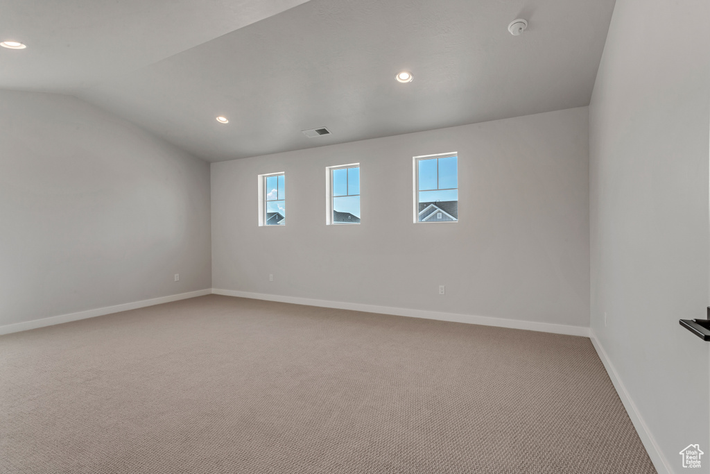Spare room with light colored carpet and vaulted ceiling