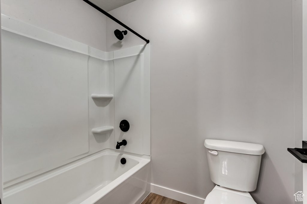 Bathroom featuring  shower combination, hardwood / wood-style flooring, and toilet