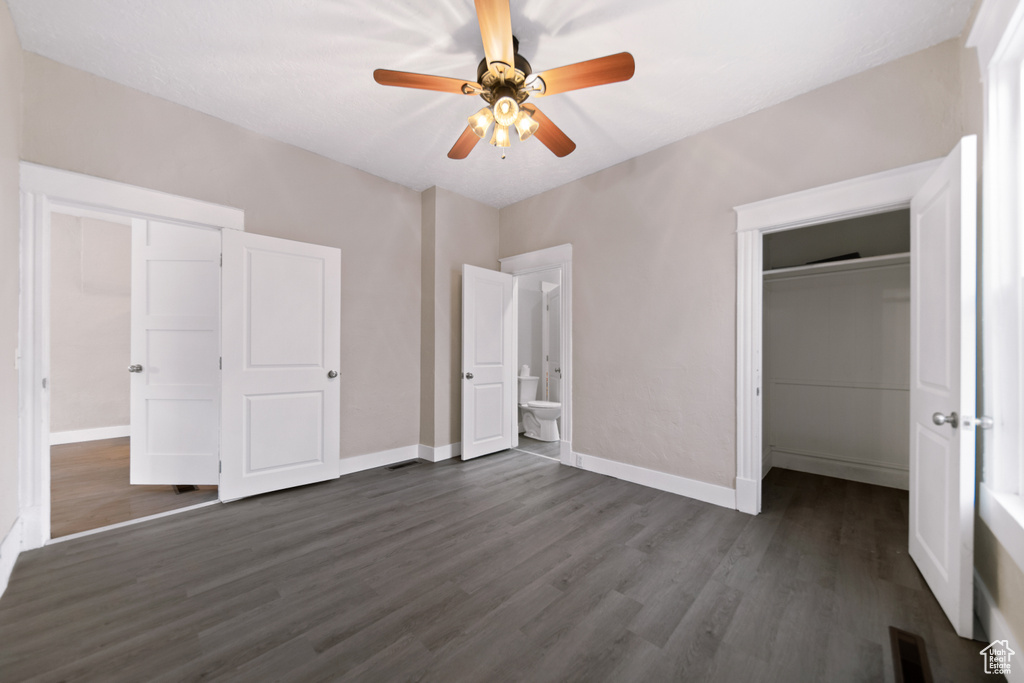 Unfurnished bedroom with dark wood-type flooring, ceiling fan, and ensuite bathroom