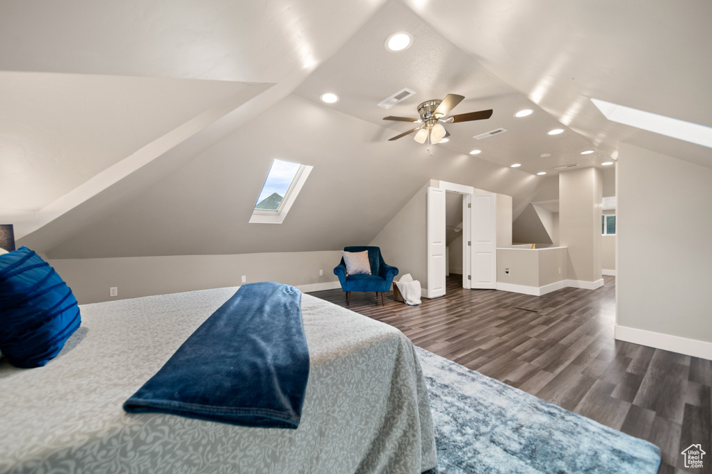 Bedroom featuring dark hardwood / wood-style flooring, ceiling fan, and lofted ceiling with skylight