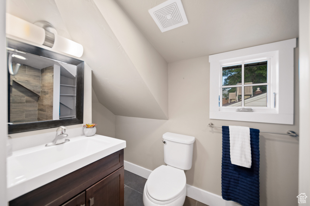 Bathroom with lofted ceiling, vanity, toilet, and tile floors