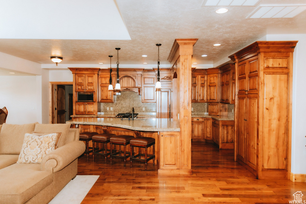 Kitchen featuring hardwood / wood-style floors, a breakfast bar area, and tasteful backsplash