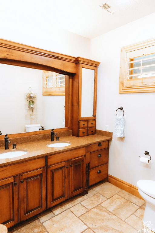 Bathroom with toilet, tile flooring, and dual vanity