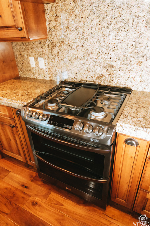 Kitchen featuring double oven range, dark wood-type flooring, and light stone counters