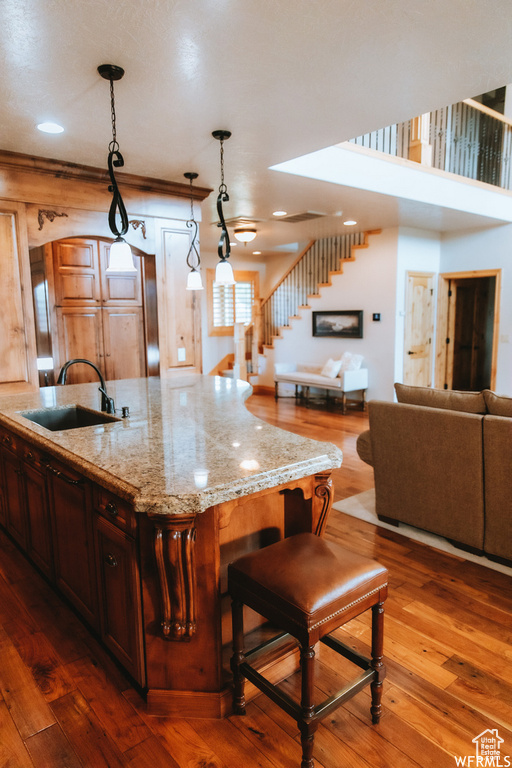 Kitchen with dark hardwood / wood-style flooring, hanging light fixtures, sink, and light stone countertops