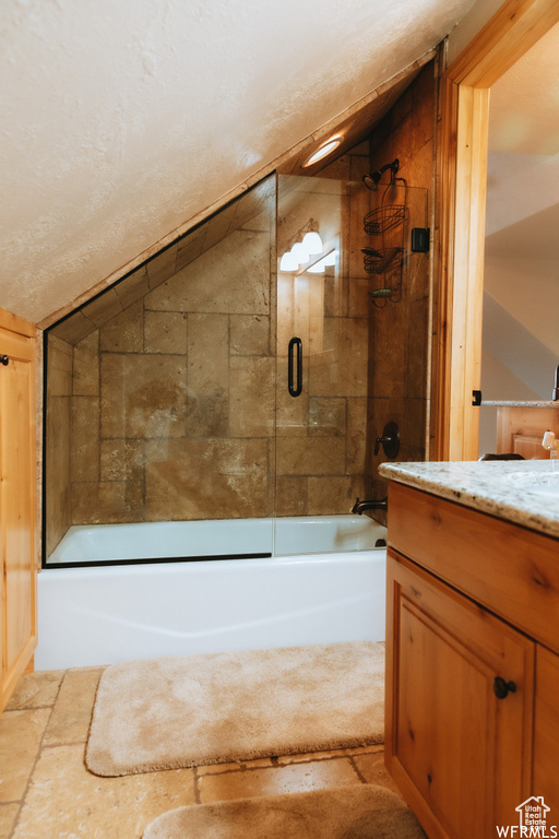 Bathroom with enclosed tub / shower combo, vanity, a textured ceiling, and lofted ceiling