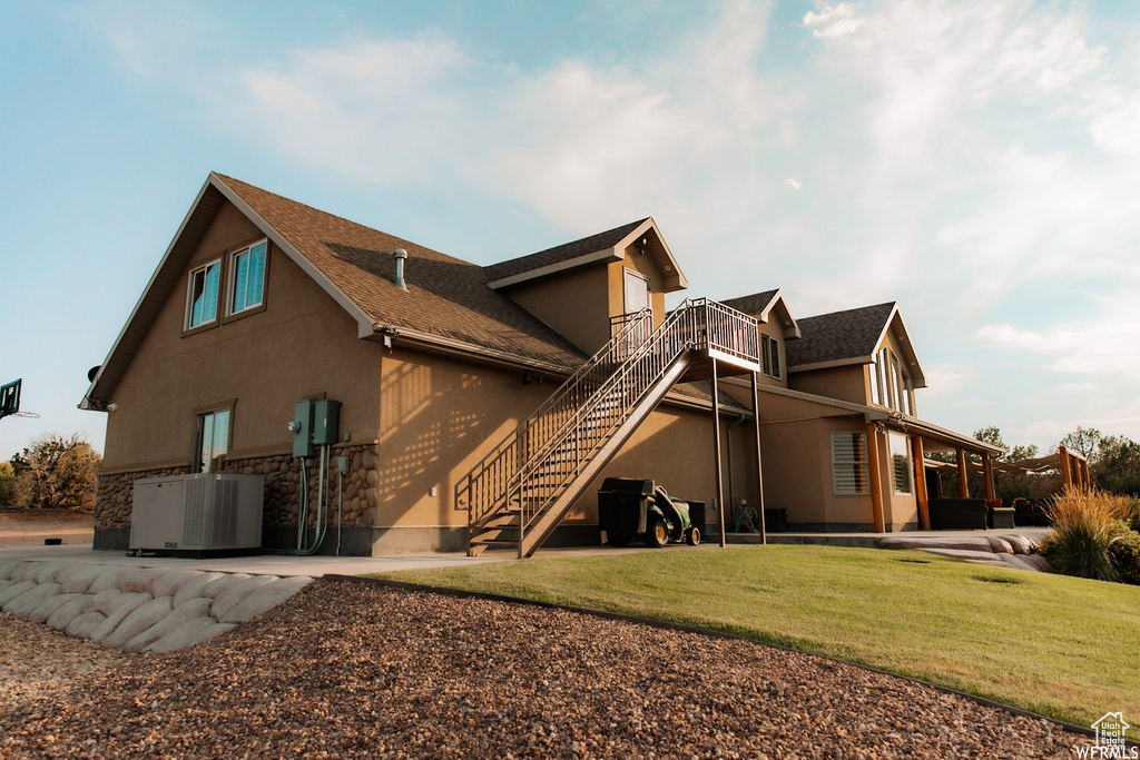 Rear view of house featuring central air condition unit, a patio, and a lawn