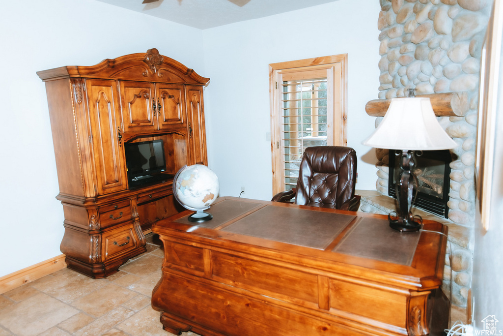 Tiled office space featuring a fireplace and ceiling fan