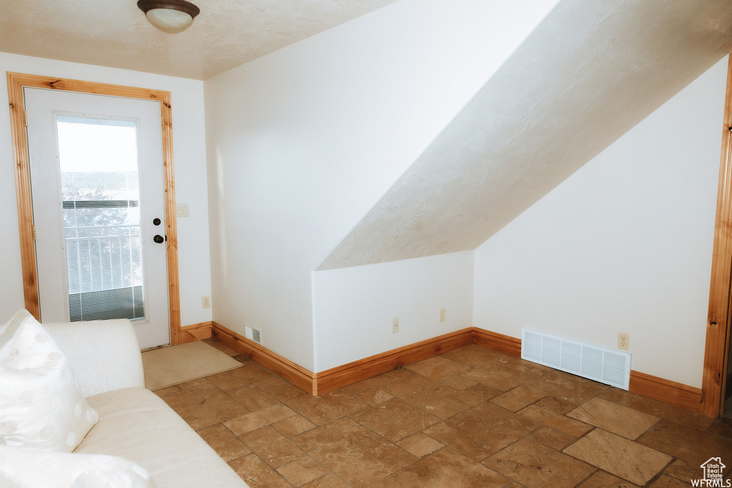 Additional living space featuring vaulted ceiling and light tile flooring