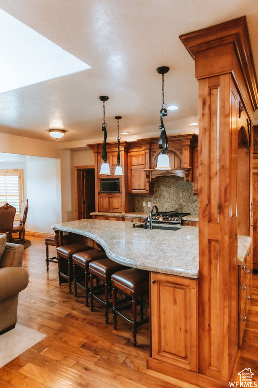 Kitchen featuring a kitchen bar, sink, tasteful backsplash, wood-type flooring, and pendant lighting