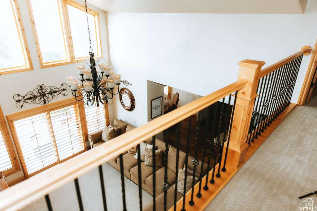 Staircase with high vaulted ceiling, a notable chandelier, and light carpet