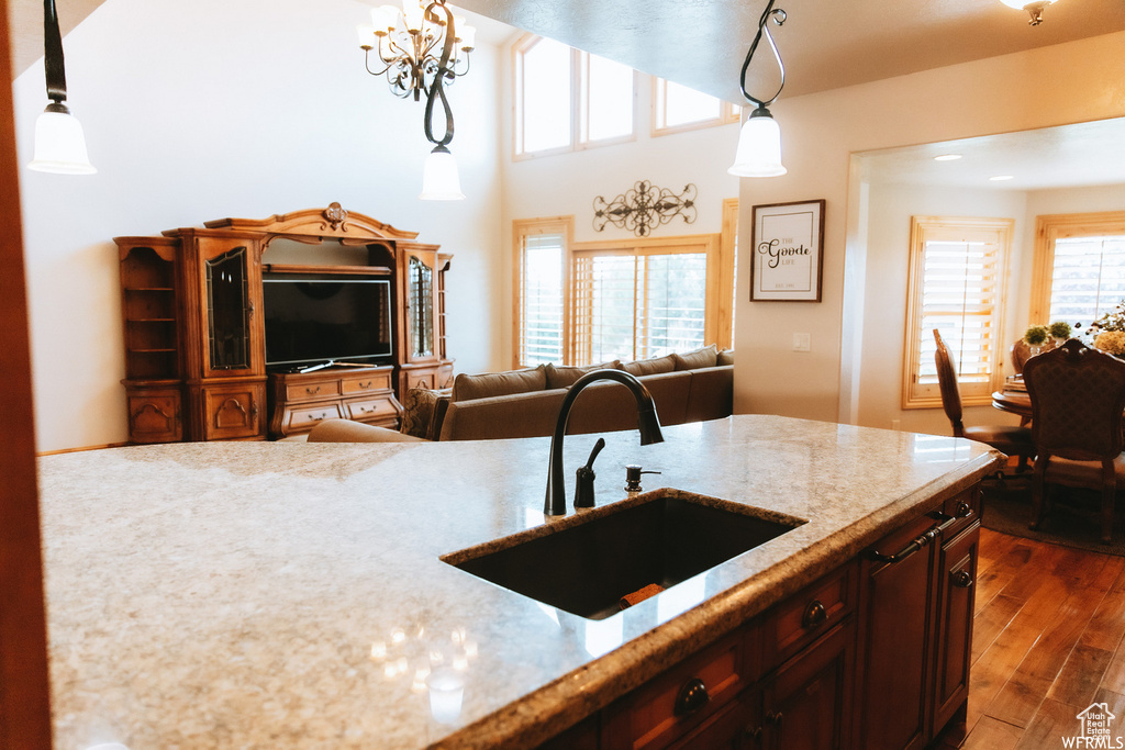 Kitchen with a healthy amount of sunlight, dark wood-type flooring, and decorative light fixtures