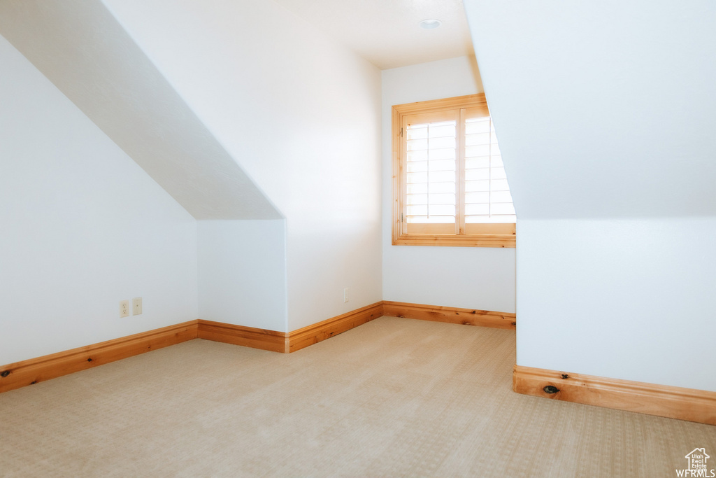 Additional living space featuring light carpet and lofted ceiling