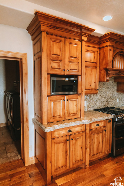 Kitchen featuring gas range, dark hardwood / wood-style flooring, backsplash, and separate washer and dryer