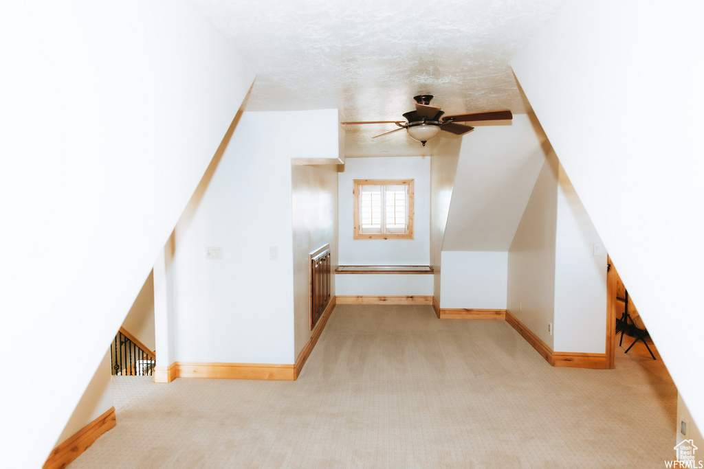 Bonus room with light colored carpet, ceiling fan, and a textured ceiling