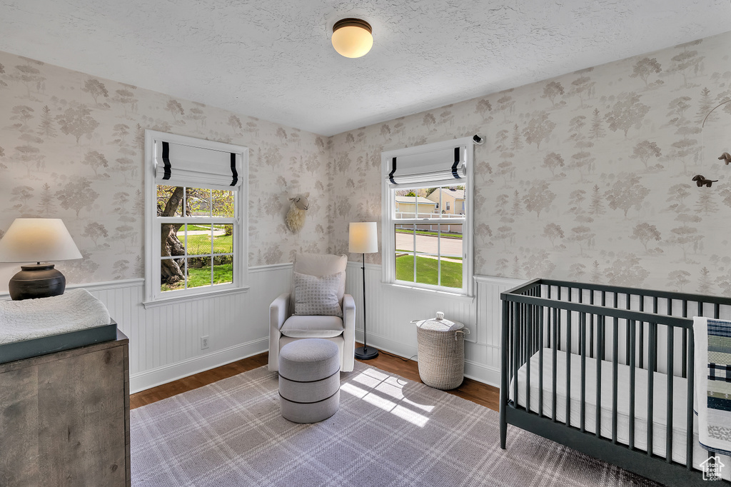 Bedroom with dark wood-type flooring, a textured ceiling, and a nursery area