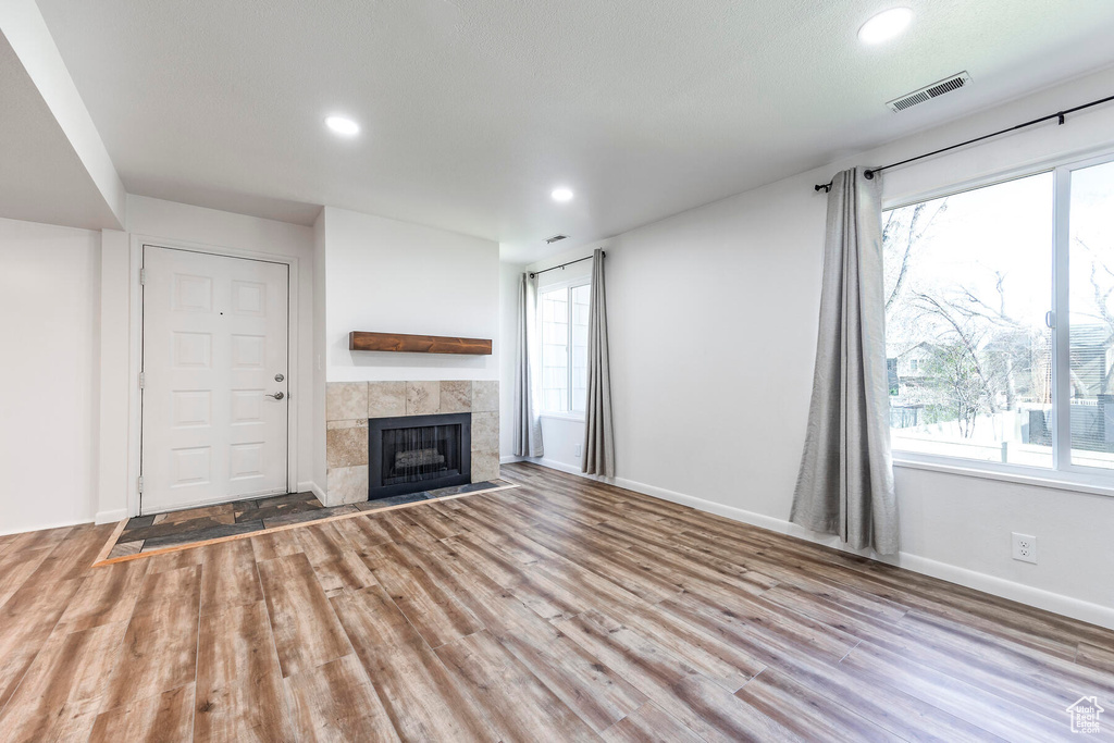 Unfurnished living room featuring light hardwood / wood-style floors and a tiled fireplace