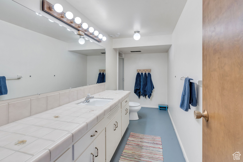 Bathroom with concrete flooring, toilet, and large vanity