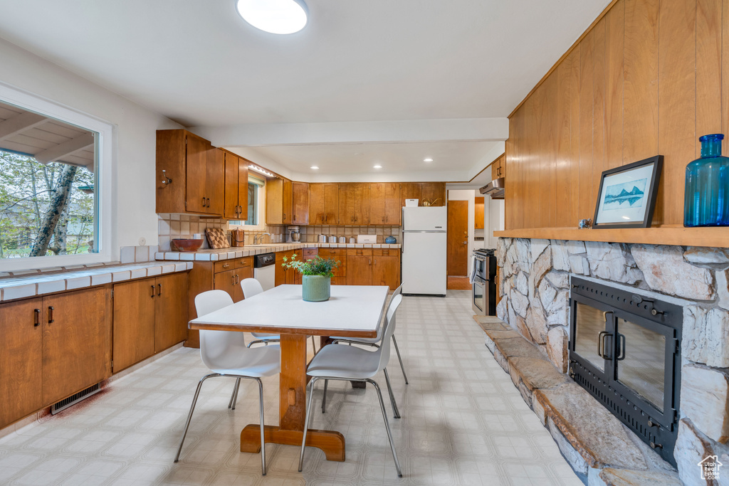 Kitchen featuring white fridge, a fireplace, tasteful backsplash, and light tile floors