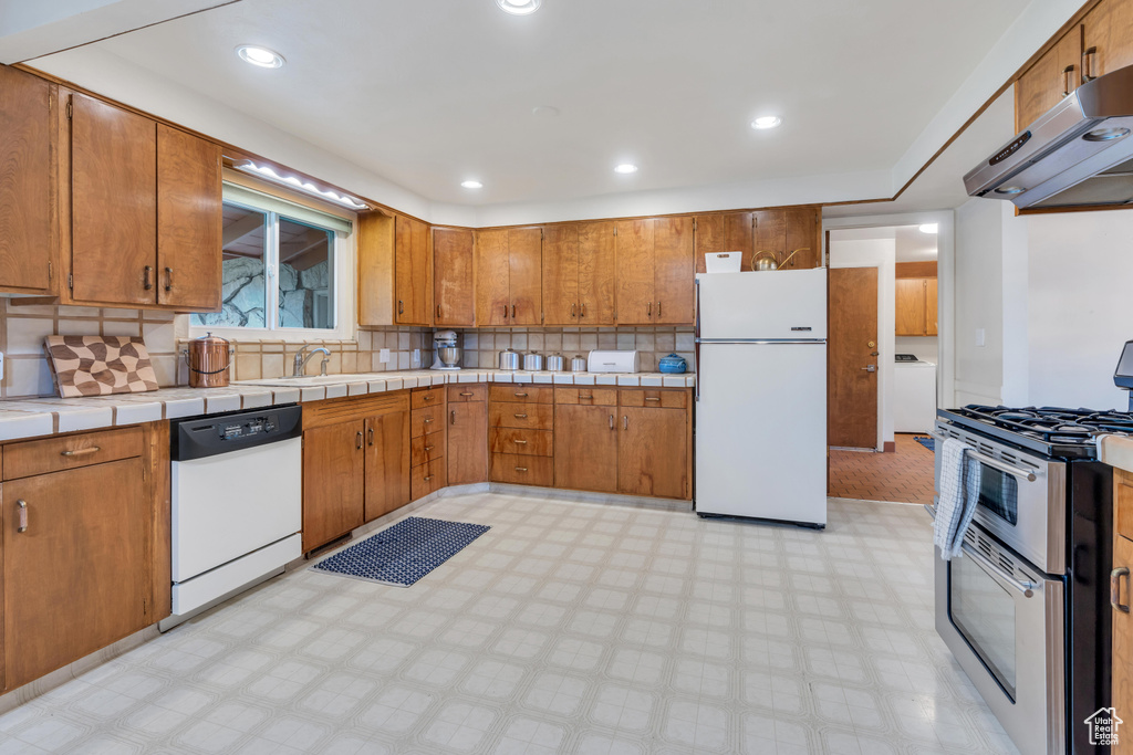 Kitchen featuring backsplash, white appliances, and light tile flooring