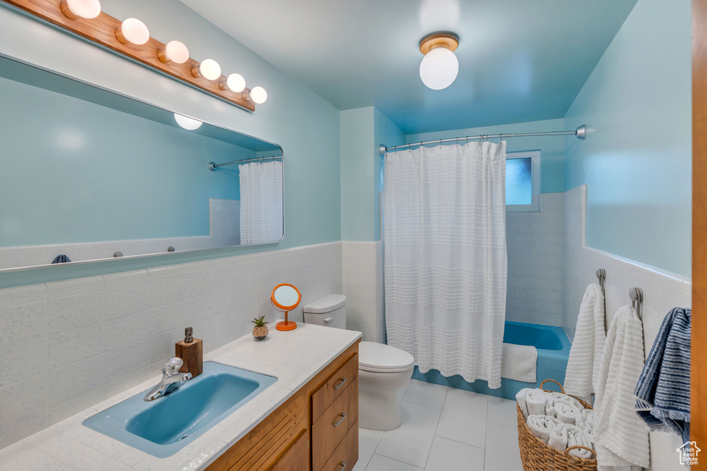 Full bathroom with tile flooring, tile walls, vanity with extensive cabinet space, tasteful backsplash, and toilet