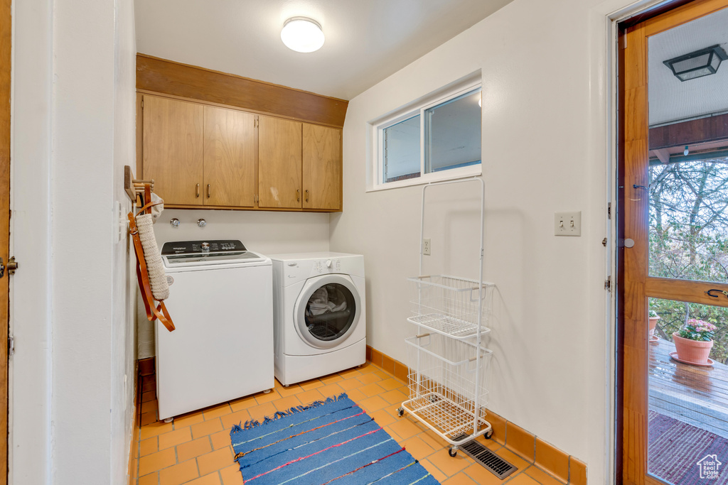 Laundry area with a healthy amount of sunlight, cabinets, independent washer and dryer, and light tile floors