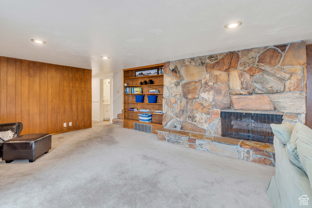 Living room featuring light colored carpet, wood walls, and a fireplace