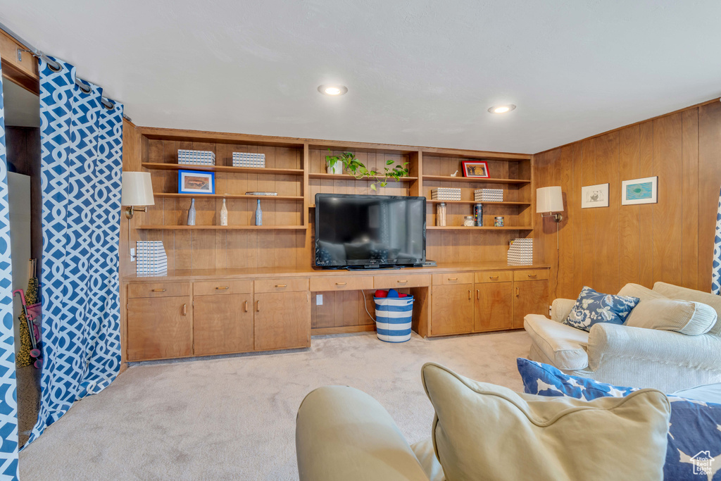 Carpeted living room featuring wood walls and built in desk