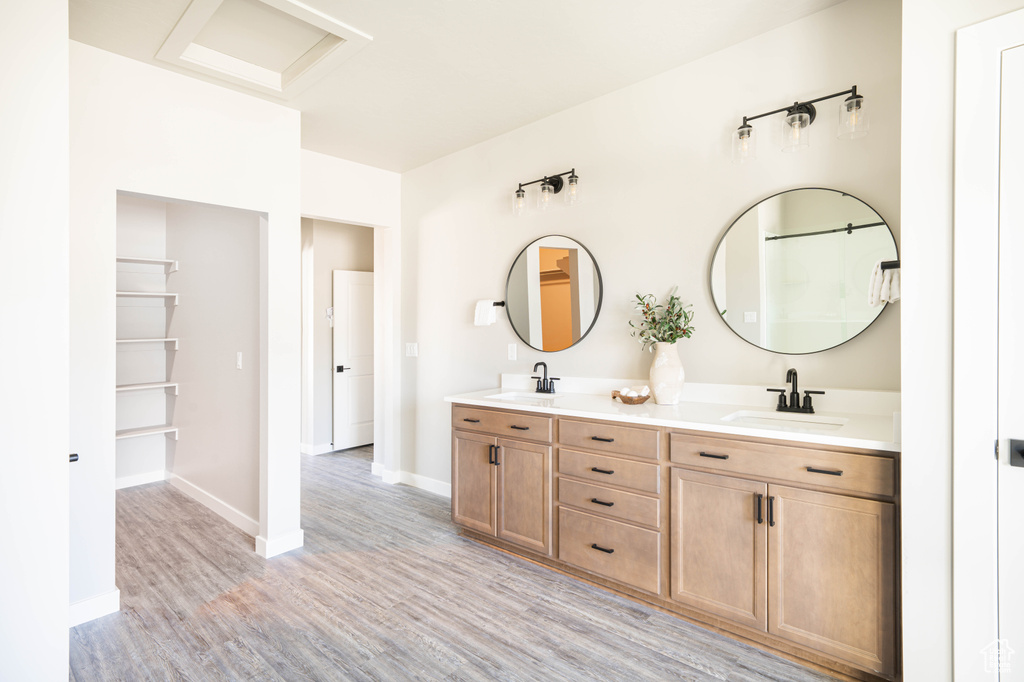 Bathroom with hardwood / wood-style floors, vanity with extensive cabinet space, and double sink
