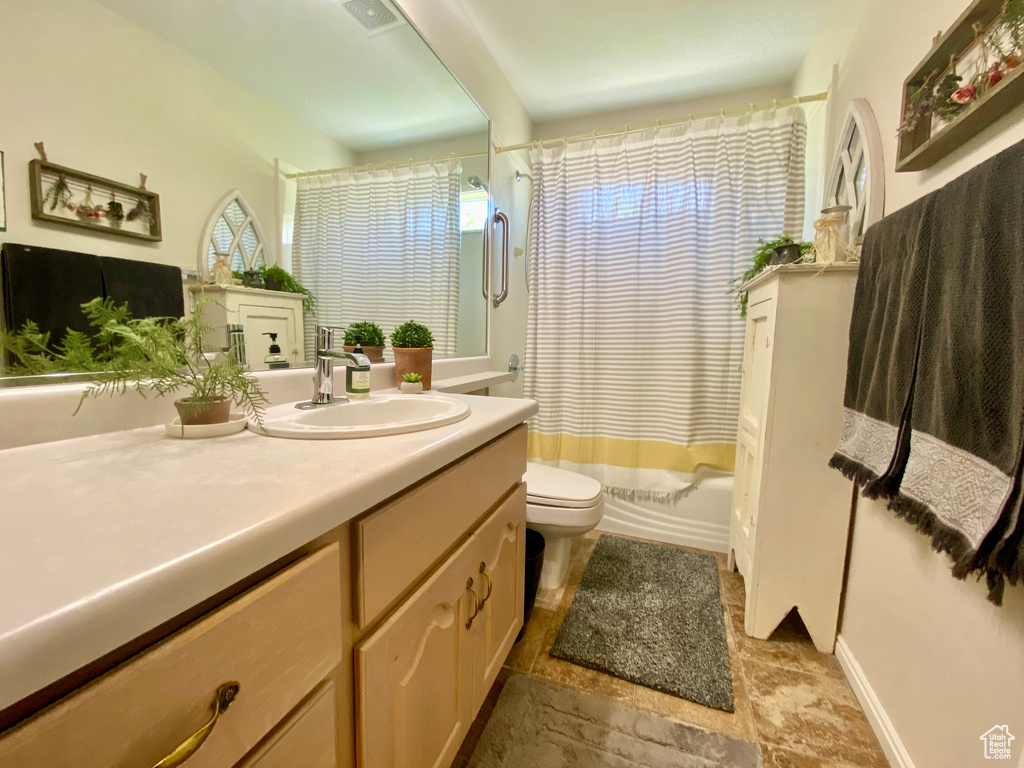 Full bathroom with vanity, tile floors, toilet, and shower / bath combo with shower curtain
