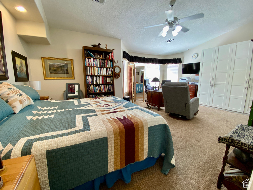 Bedroom with light colored carpet, a textured ceiling, and ceiling fan