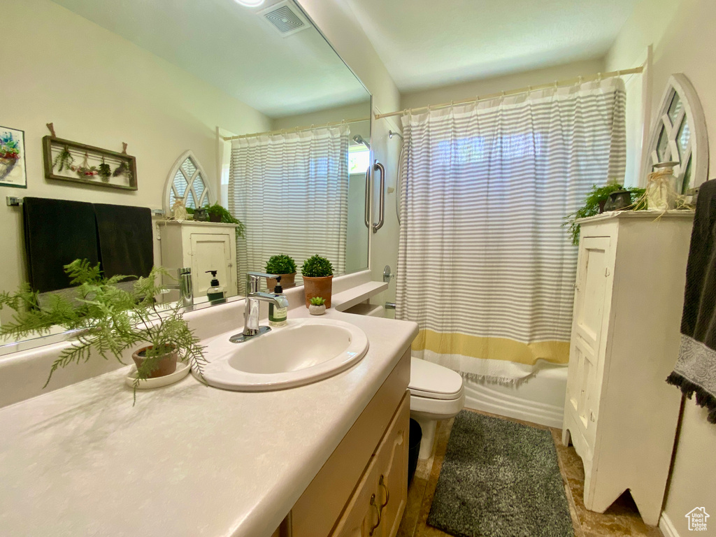 Full bathroom featuring vanity with extensive cabinet space, shower / tub combo, toilet, and tile floors