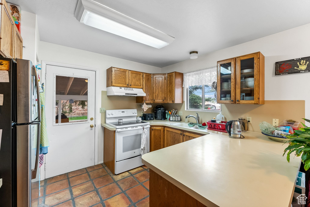 Kitchen featuring stainless steel refrigerator, kitchen peninsula, sink, dark tile flooring, and white electric range oven