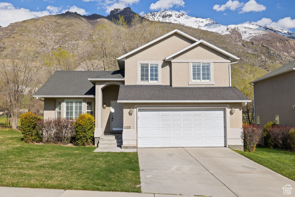 View of front of property with a front yard, a garage, and a mountain view