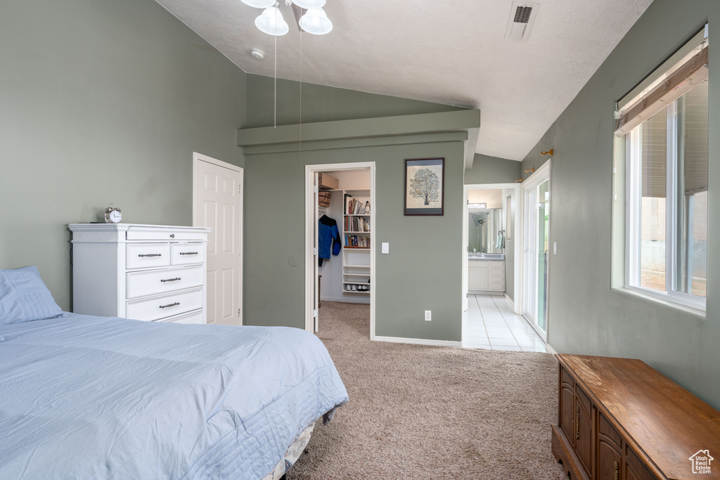 Carpeted bedroom with a closet, lofted ceiling, ensuite bathroom, and a spacious closet