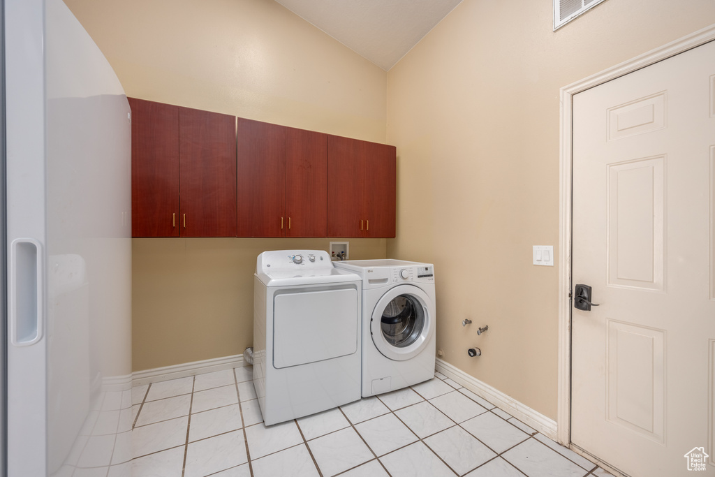 Clothes washing area featuring washer and clothes dryer, hookup for a washing machine, cabinets, and light tile floors
