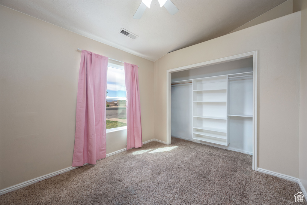 Unfurnished bedroom featuring light colored carpet, ceiling fan, vaulted ceiling, and a closet