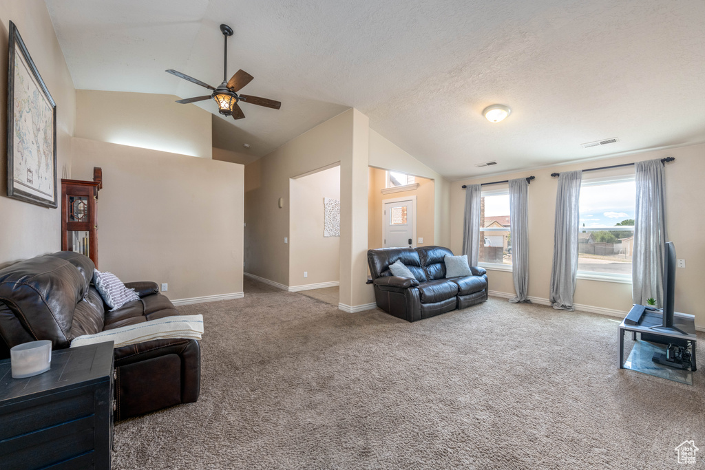 Living room with ceiling fan, vaulted ceiling, and light carpet