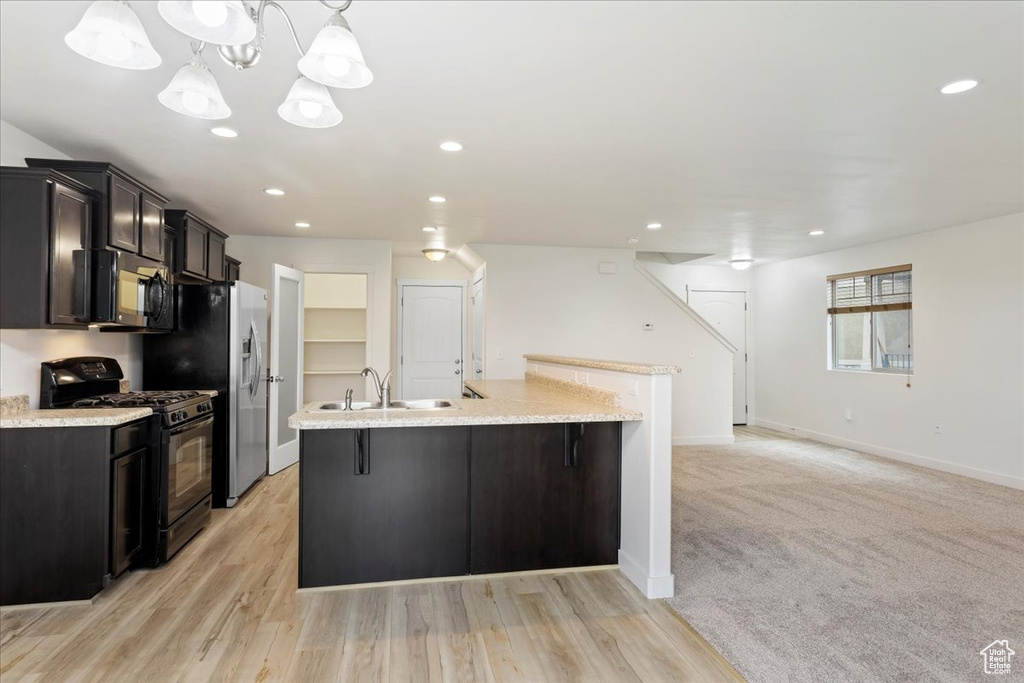 Kitchen with light carpet, black appliances, sink, and decorative light fixtures