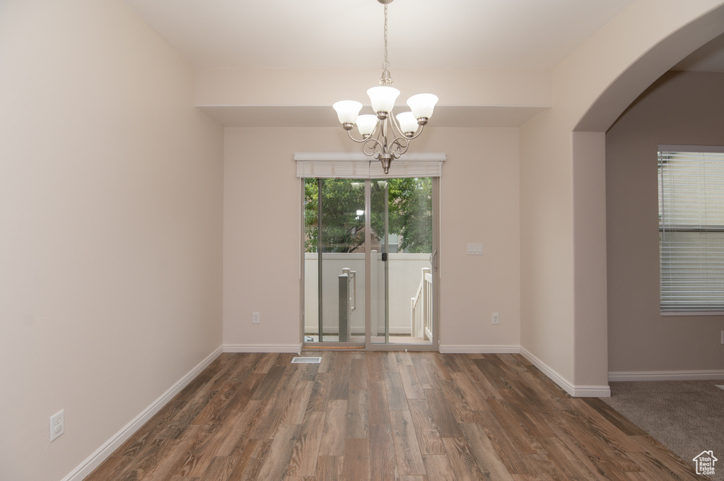 Unfurnished room featuring dark hardwood / wood-style flooring and an inviting chandelier