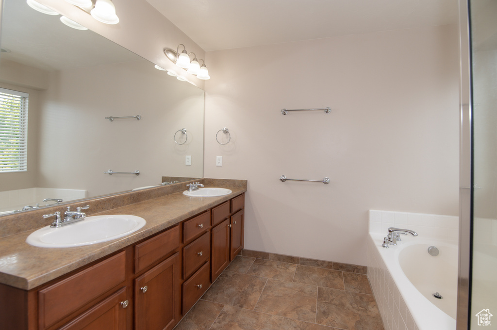 Bathroom featuring tile floors, double vanity, and tiled tub