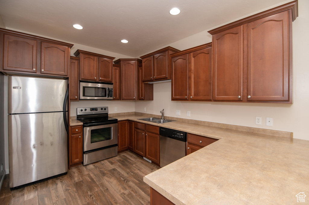 Kitchen with dark hardwood / wood-style flooring, appliances with stainless steel finishes, and sink