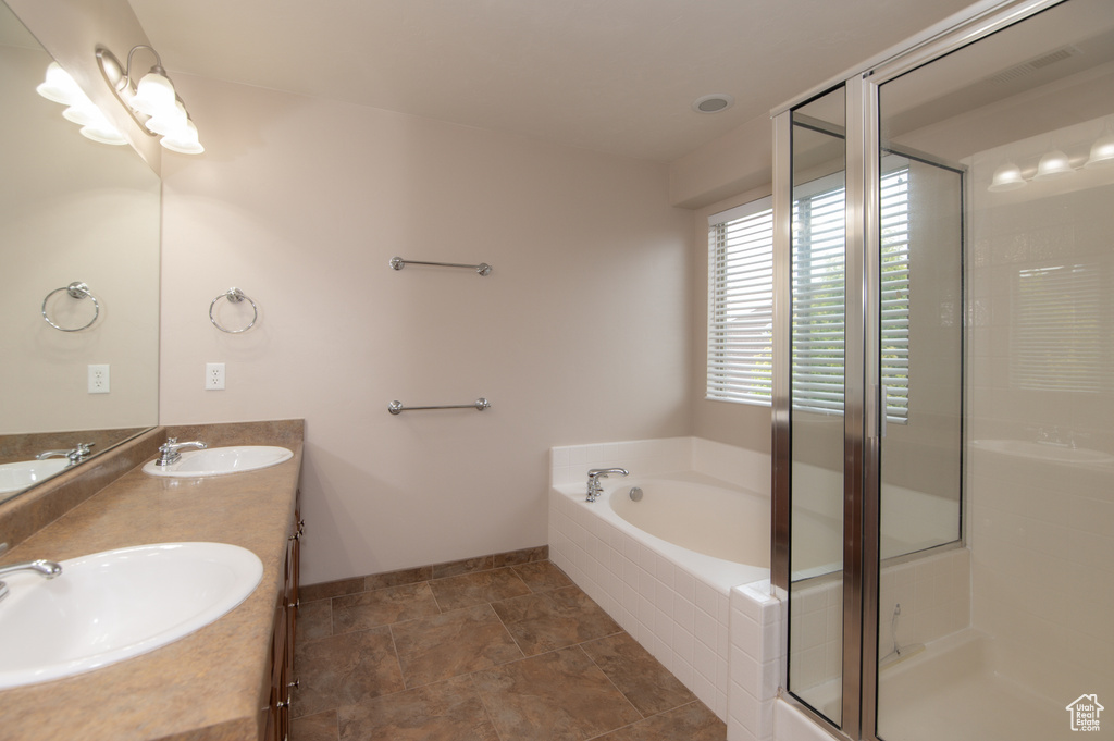 Bathroom featuring double sink, tile floors, oversized vanity, and plus walk in shower